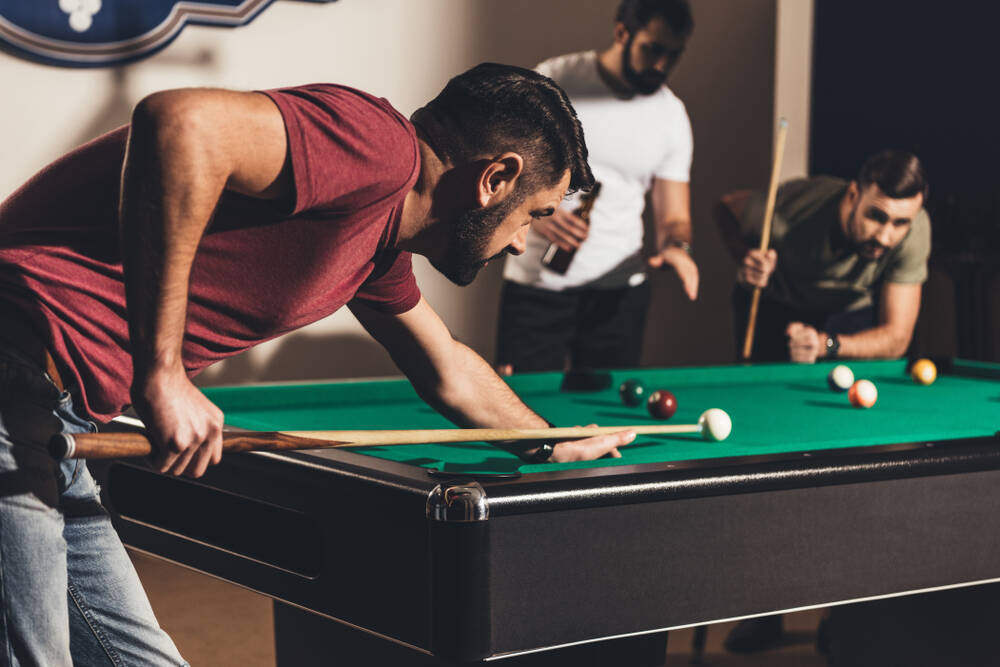 A man playing pool with friends.